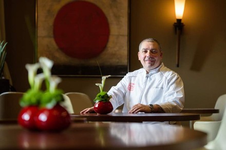 Sternekoch Christian Bau sitzt lächelnd an einem Tisch