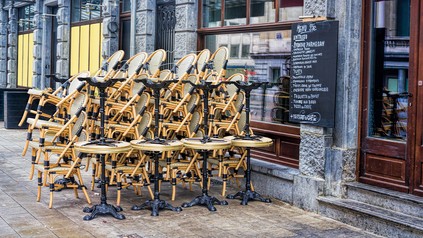 Stühle und Tische stehen gestapelt vor geschlossenem Restaurant