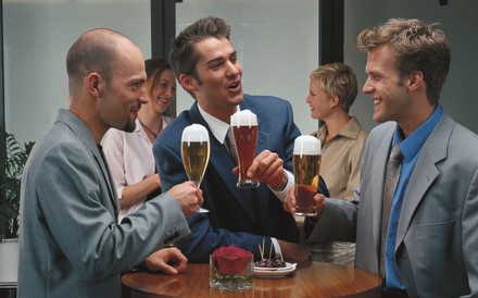 Drei Männer trinken Bier in einem Lokal.