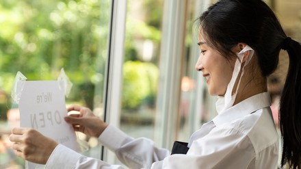Servicekraft hängt „Geöffnet“-Schild an die Restauranttür