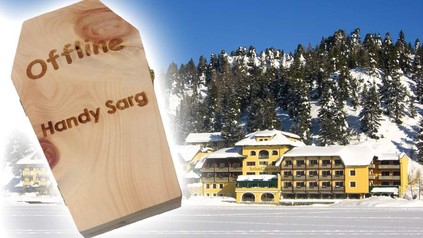 Das Hotel Jägerwirt von außen und ein Holzsarg auf dem Offline Handy Sarg steht