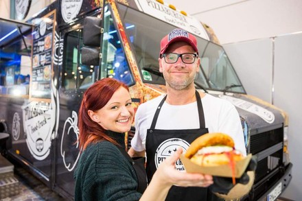 Zwei Menschen auf einer Messe, die vor einem Foodtruck etwas essen