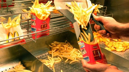 Eine Hand, die McDonald's-Pommes ein tütet. Origineller Rollentausch: Am Ray-Kroc-Tag stehen die Büros leer, da alle Verwaltungskräfte im Restaurant mitarbeiten müssen.