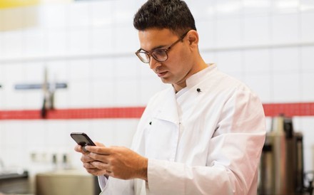 Chefkoch mit Smartphone im Restaurant