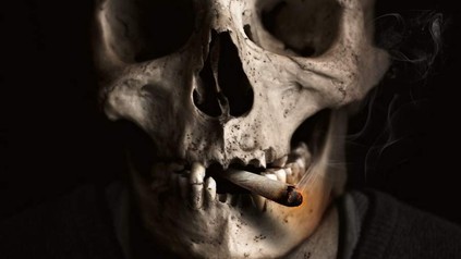 Ein menschlicher Totenschädel mit einer Zigarette im Mund