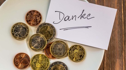 Teller mit Geldmünzen und einem Danke-Zettel