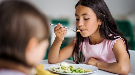 Zwei Mädchen, die in einer Schulkantine zu MIttag essen