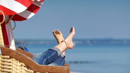 Frau legt ihre Füße im Strandkorb hoch