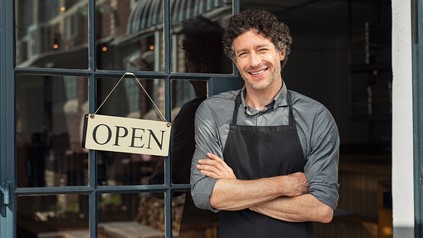 Mann steht am Eingang seinen Restaurants neben dem Open-Schild
