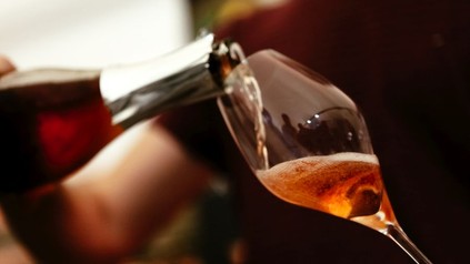 Ein Glas Rosé-Sekt wird eingeschenkt