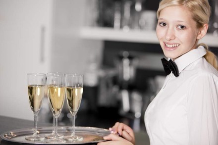 Eine junge Servicekraft beim Servieren von Sekt