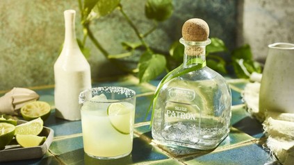 Margarita neben einer Tequila-Flasche und klassischen Zutaten
