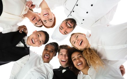 Junge Köche und Kellner lachen