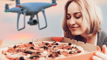 Eine Frau öffnet einen Pizzakarton, während über ihr eine Drohne schwebt