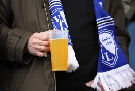 Mann hält Bierbecher in Stadion