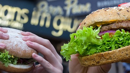 Zwei Cheeseburger vor den beioden Logos von Hans im Glück und Peter Pane
