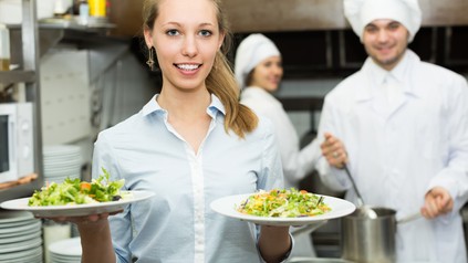 Kellnerin verlässt mit 2 vollen Tellern die Küche