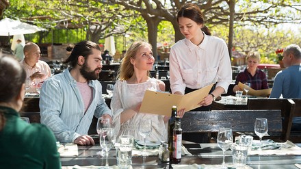 Kellnerin zeigt Speisekarte im Außenbereich