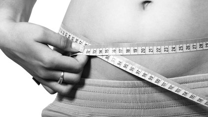 Frau hält sich Maßband um den Bauch