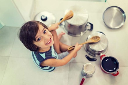 Kind schlägt mit Kochlöffeln auf Kochtöpfe