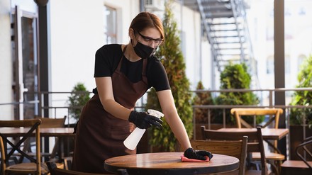 Gastronomin desinfiziert Tische
