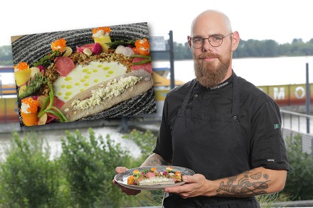 Küchenchef Sebastian Kumpmann mit einer Fischkreation auf einem Teller