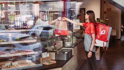 Lieferdienstfahrerin holt Speisen im Restaurant ab