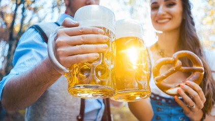 Mann und Frau in Tracht stoßen mit Bier an.