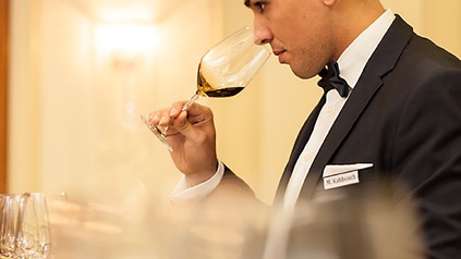 Eine Servicekraft riecht vor dem Servieren an einem Glas Wein