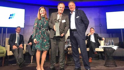 Eine Gruppe Menschen, die auf einer Bühne Urkunden präsentieren