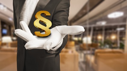 Ein Kellner mit einem Paragrafenzeichen in der Hand