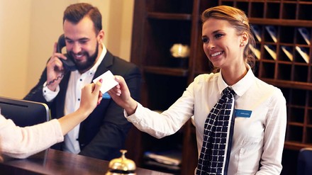 Hotelrezeption: Rezeptionistin übergibt Schlüsselkarte