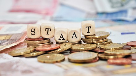 Geld, auf dem Buchstabenwürfel liegen, die das Wort Staat bilden