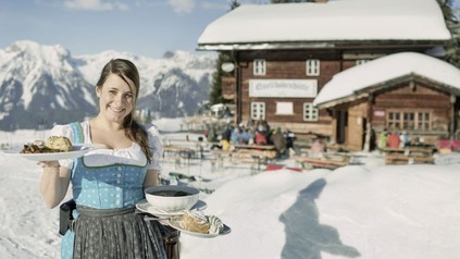 Kellnerin im Winter vor einer Almhütte