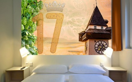 Hotelbett mit Aussicht auf den Grazer Uhrturm