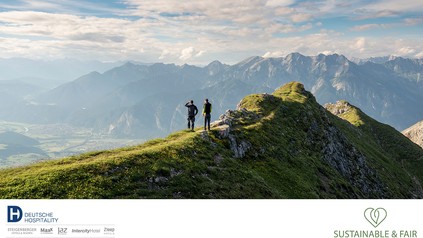 Blick auf einen Berggipfel auf dem zwei Wanderer stehen