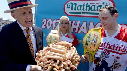 Alter Mann hält Teller voller Hotdogs in Händen