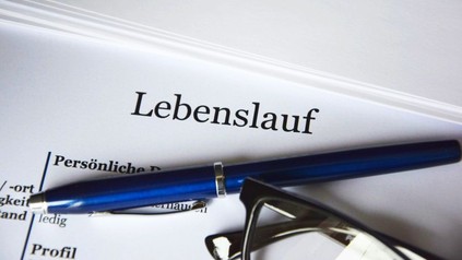 Ein Lebenslauf auf dem ein Stift und eine Brille liegen