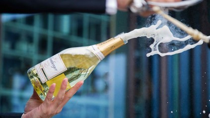 Eine Flasche Sekt wird mit einem Säbel sabriert