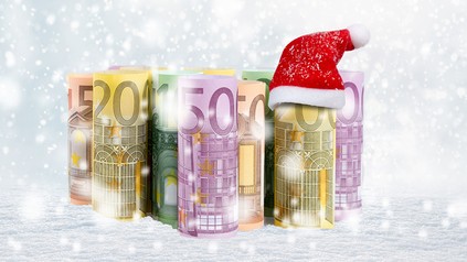 Einige Geldscheine im Schnee und eine Nikolausmütze