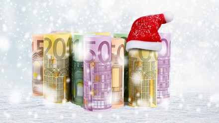 Einige Geldscheine im Schnee und eine Nikolausmütze