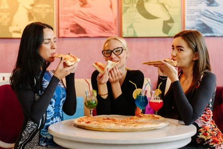 Drei Frauen essen Pizza in einem Restaurant