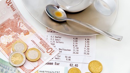 Auf einem Tisch befindet sich eine Kaffeetasse und Geldscheine