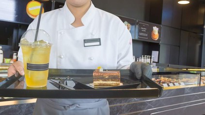 Bedienung hält Tablett mit Kuchen und Getränk