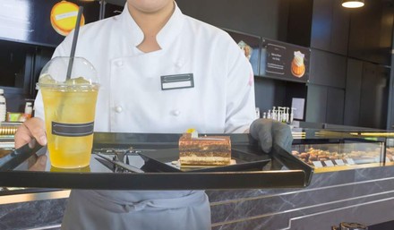 Bedienung hält Tablett mit Kuchen und Getränk