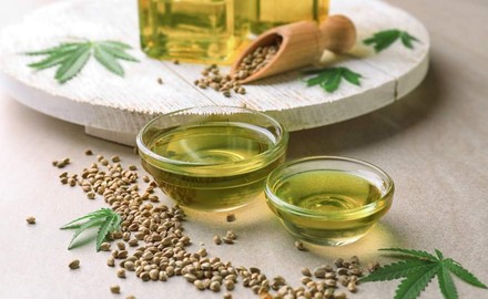 Zwei Schälchen mit Öl und Cannabisblätter drumherum