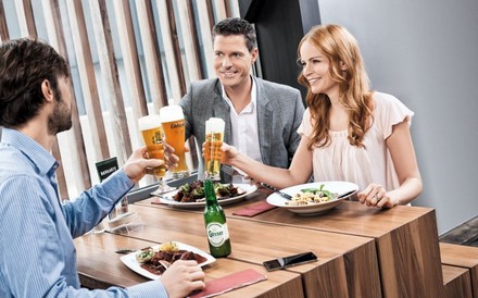 Drei Freunde stoßen beim Essen mit Bier an.