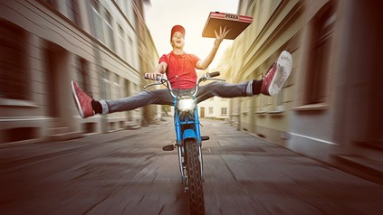 Ein Pizzafahrer auf dem Moped rast durch eine Straße