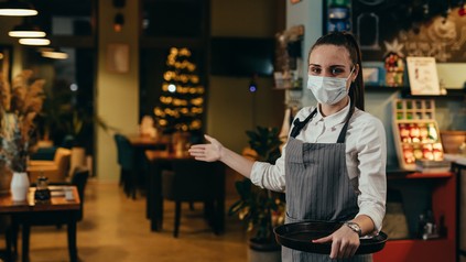 Junge Servicekraft bittet Gäste einzutreten