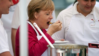 Kanzlerin Angela Merkel mit mehreren Köchen in einer Küche